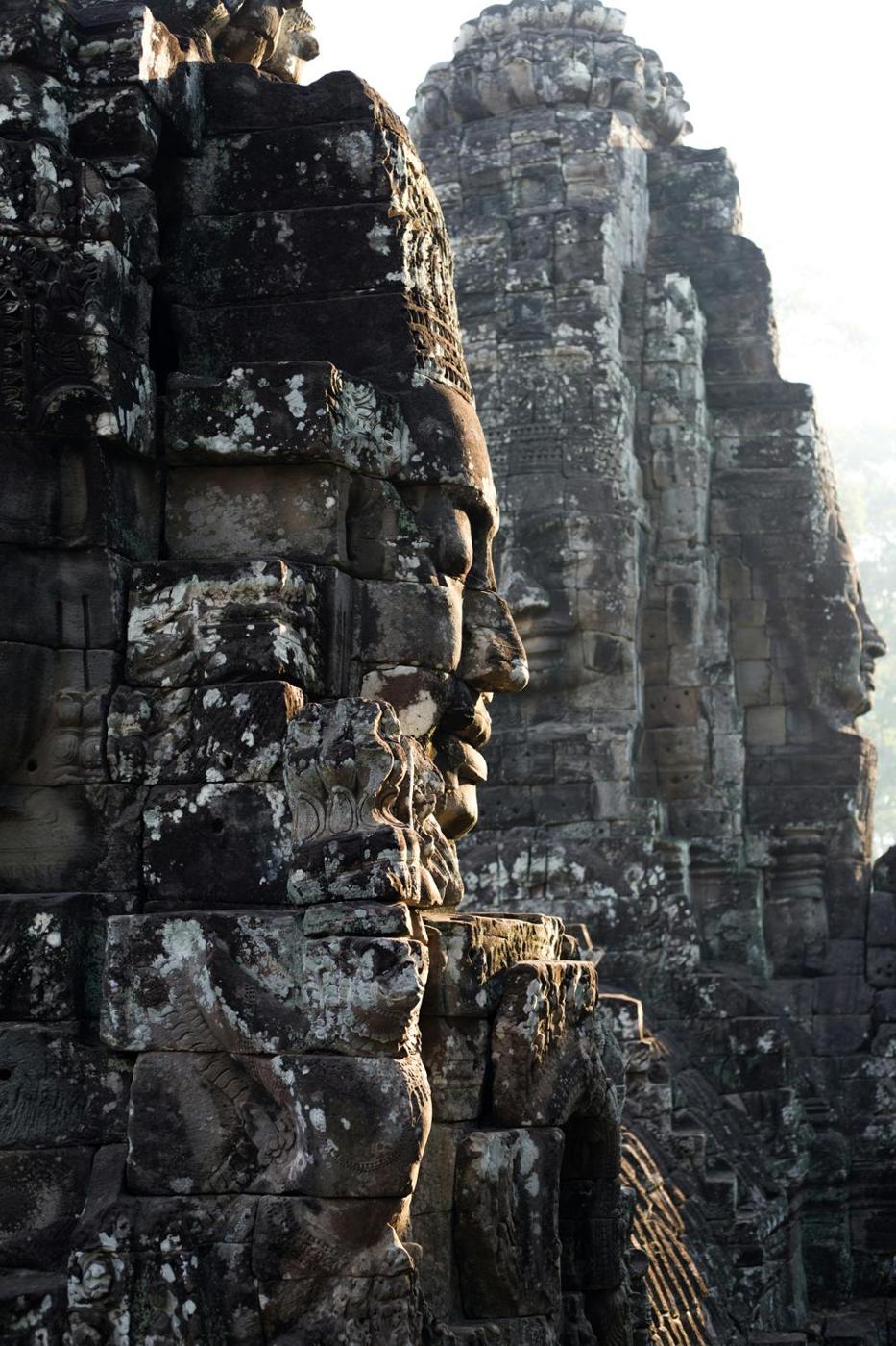 Carved stone faces of the Bayon temple at Angkor in morning haze