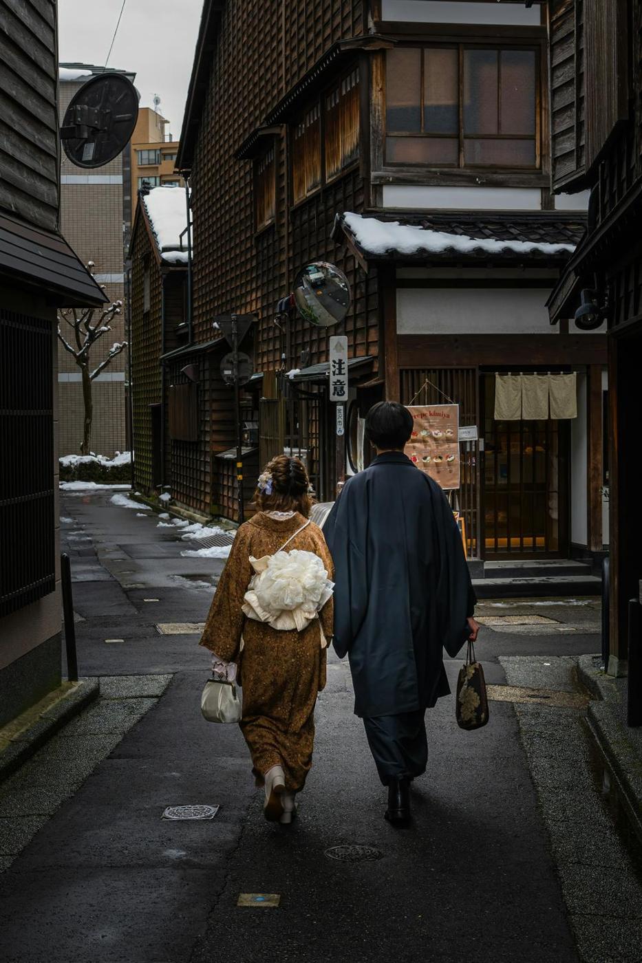 A couple in kimono walking through Kanazawa&rsquo;s old teahouse district after snowfall